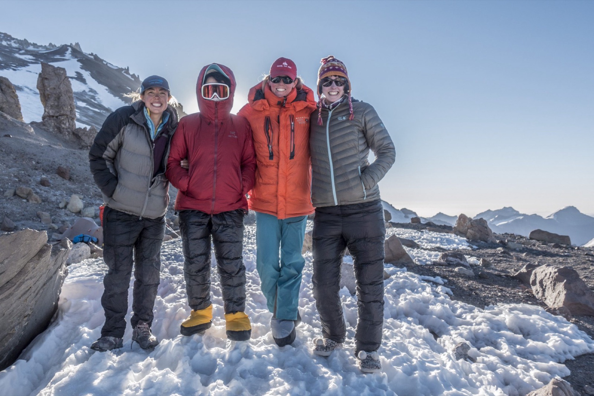 Four women in down jackets standing together on snow on Aconcagua