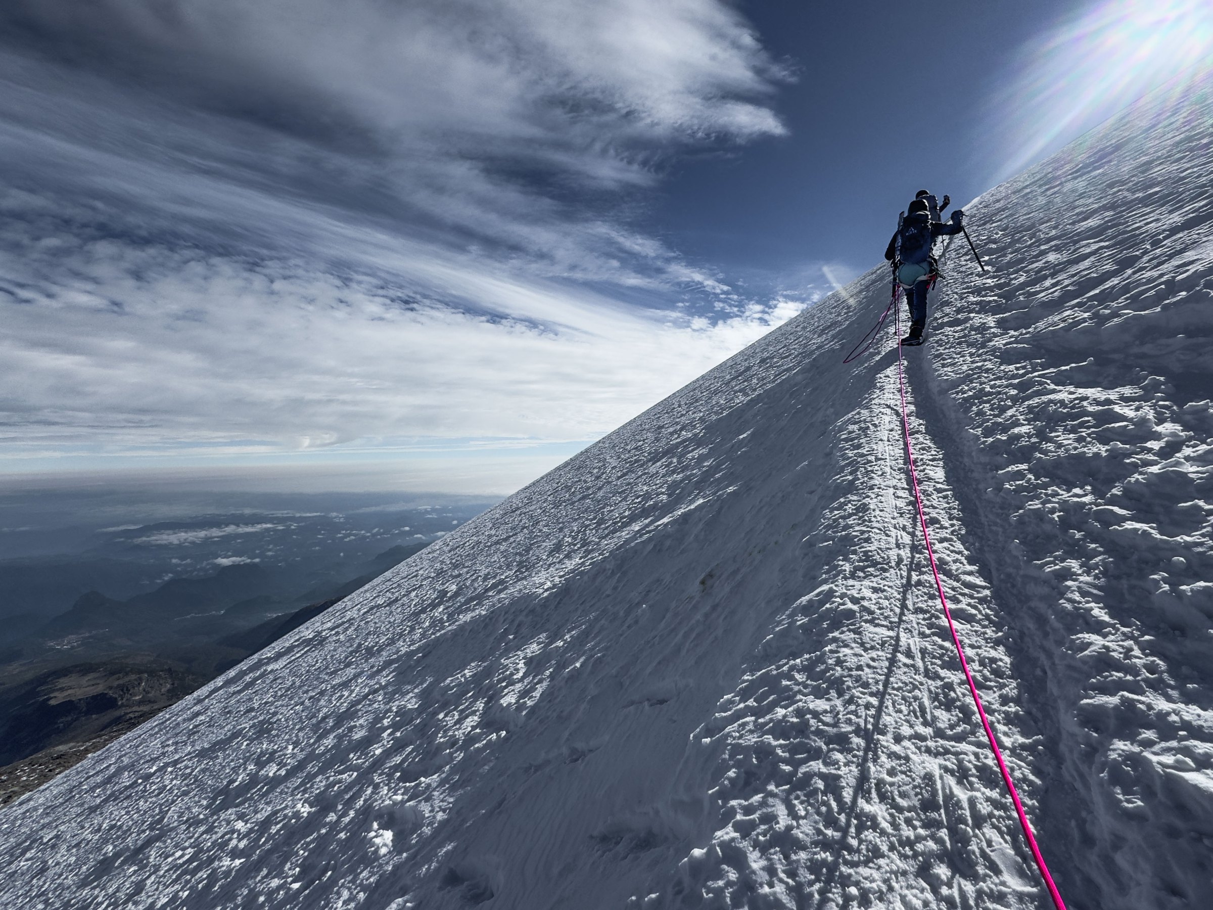 Roped climbers on the steep summit glacier of Pico de Orizaba above a sea of clouds